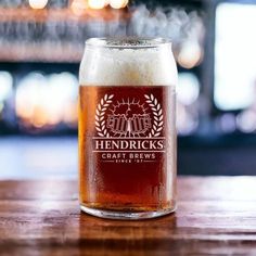 a glass filled with beer sitting on top of a wooden table