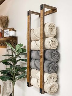 a towel rack with towels hanging on the wall and a potted plant next to it