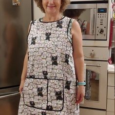 an older woman standing in front of a refrigerator wearing a dress with cats on it