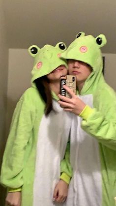 two people dressed in frog costumes taking a selfie with a cell phone while standing next to each other