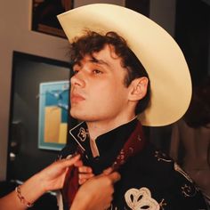 a man wearing a white cowboy hat and holding his hand to his chest while looking off into the distance