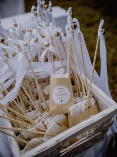 a box filled with lots of white and gold toothpicks on top of a table