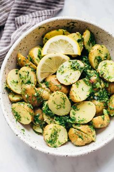 a white bowl filled with potatoes and lemon slices