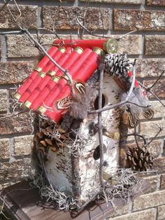 a birdhouse with red roof and pine cones on it's roof next to a brick wall