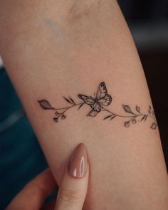 a woman's arm with a butterfly and flower tattoo on the left side of her arm