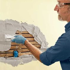 a man in blue shirt and gloves painting a wall