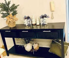 a black console table with two baskets on top and one shelf holding vases next to it