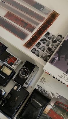 several old cameras and film strips on a table next to some books, magazines, and photos