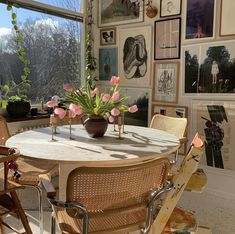 a dining room table with chairs around it and pictures on the wall behind it that are covered in pink tulips