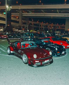 a group of cars parked in a parking lot next to an overpass at night