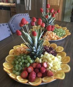 two plates filled with fruit and pineapples on top of a dining room table