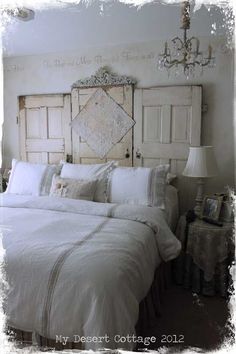 a bed with white linens and pillows in a bedroom next to a chandelier