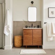 a bathroom with a wooden cabinet, mirror and towels on the rack next to it