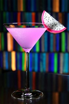 a pink martini with a slice of watermelon on the rim and colorful background