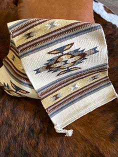 a brown and white blanket sitting on top of a fur covered floor next to pillows