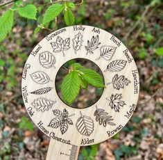 a wooden wind chime with leaves and words engraved on the front, hanging from a tree branch