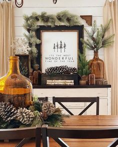 a dining room table decorated for christmas with pine cones and greenery