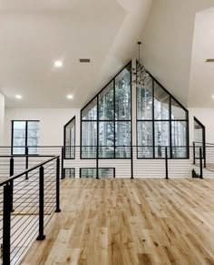 an empty room with wooden floors and glass windows on the wall, along with black railings