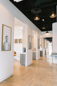 an empty room with white walls and wooden floors, framed pictures on the wall above it