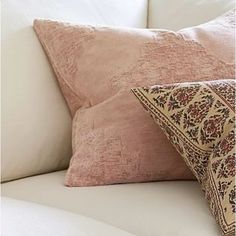 two pillows sitting on top of a white couch