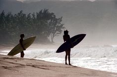 two people with surfboards standing on the beach