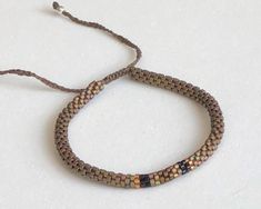 a bracelet that is made out of brown and black seed beads on a white surface