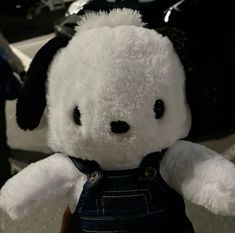 a white teddy bear wearing overalls and a black hat on top of it's head