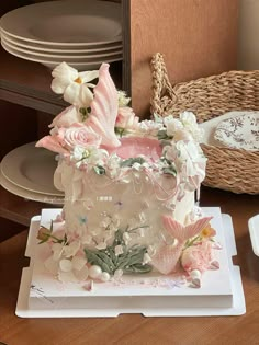 a white cake with pink flowers and butterflies on it sitting on top of a table