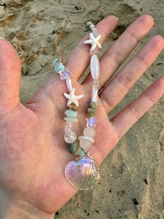 a hand is holding some glass beads and seashells