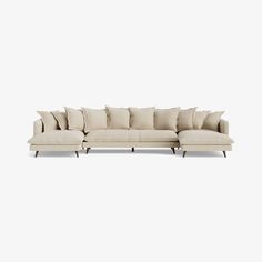 a large sectional couch with pillows on the top and bottom, sitting in front of a white