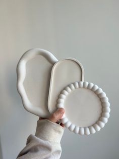 a person holding two white plates in their hand, one is shaped like an elephant