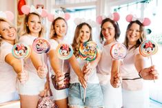 a group of women holding lollipops with mickey mouse heads on them and smiling at the camera