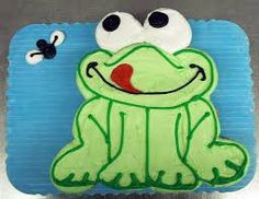 a cake shaped like a frog sitting on top of a table next to a butterfly