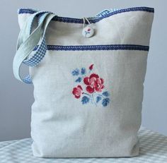 a white bag with red and blue flowers on the front is sitting on a checkered tablecloth