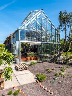 a glass house surrounded by trees and plants