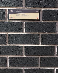 a close up of a brick wall with a sign attached to the side of it