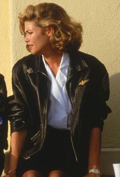 two women standing next to each other in front of a white wall wearing black leather jackets