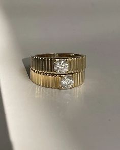 two gold wedding bands with three diamonds on each band, sitting on a white surface