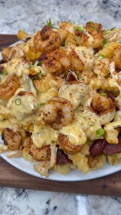 a white plate topped with pasta covered in cheese and shrimp next to a wooden cutting board