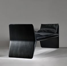 a black chair sitting on top of a white floor next to a pillow in front of it