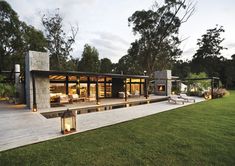 a modern house in the middle of a lush green field at dusk with lights on