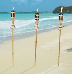 three candles are standing in the sand at the beach