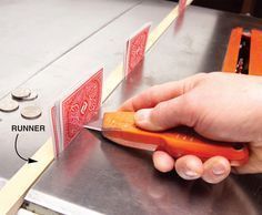 a person cutting carrots with a knife on top of a metal counter next to coins