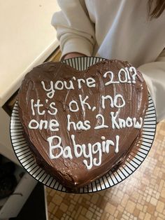 a woman holding a chocolate cake with writing on it