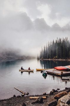 two canoes are docked on the shore of a lake