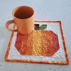 a mug sits on top of a quilted place mat with a coffee cup in the middle