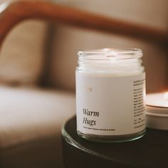 a white candle sitting on top of a table next to a glass jar filled with liquid