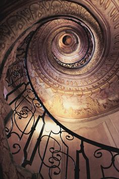 a spiral staircase with wrought iron railings leading up to the ceiling and light fixture