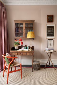 a room with a desk, chair and pictures on the wall above it that is decorated in pink tones