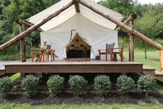 a tent set up in the middle of a field with chairs and tables around it